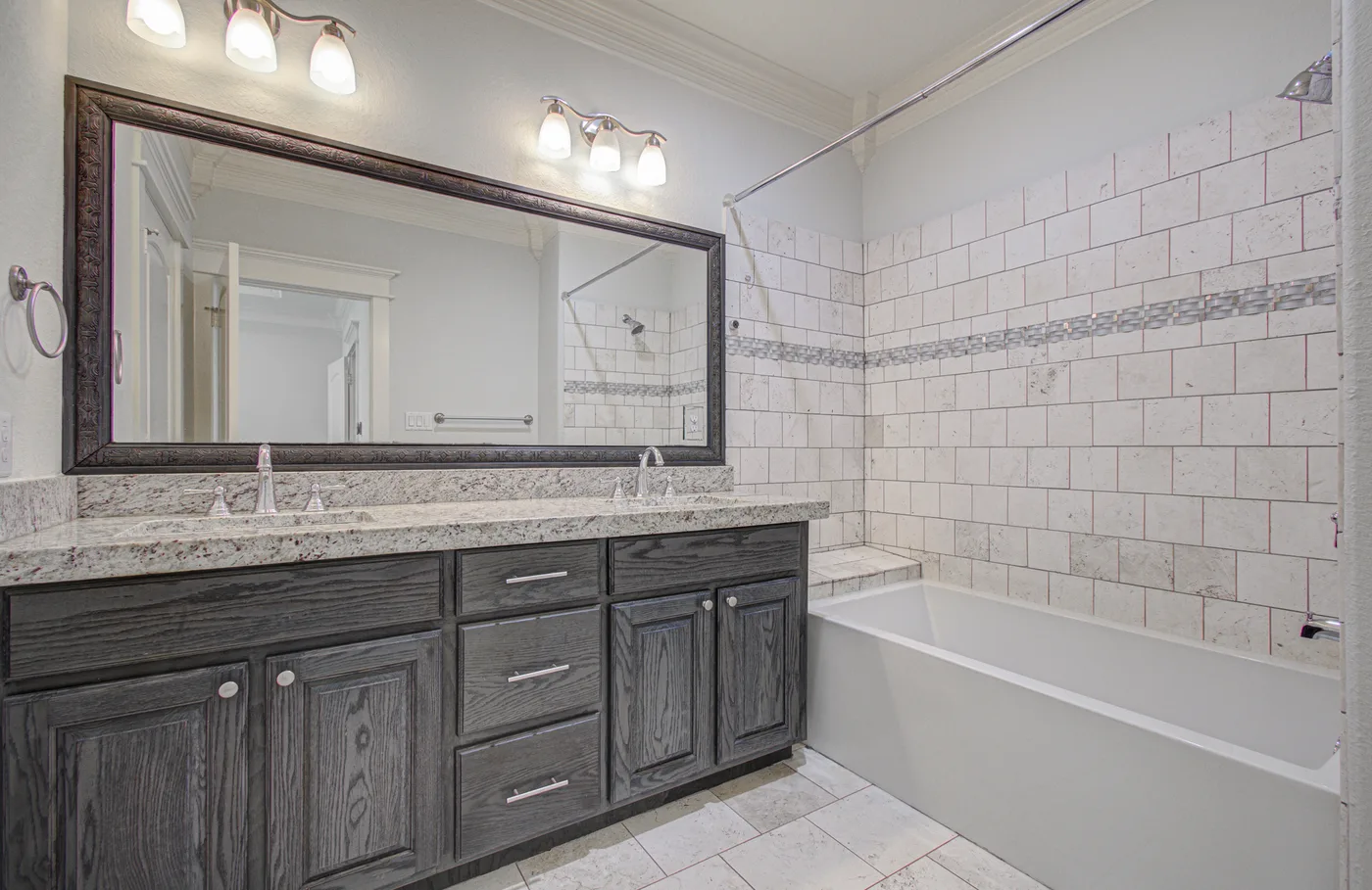 Updated bathroom with tiled tub and dark wood vanity in a Houston Heights rental home