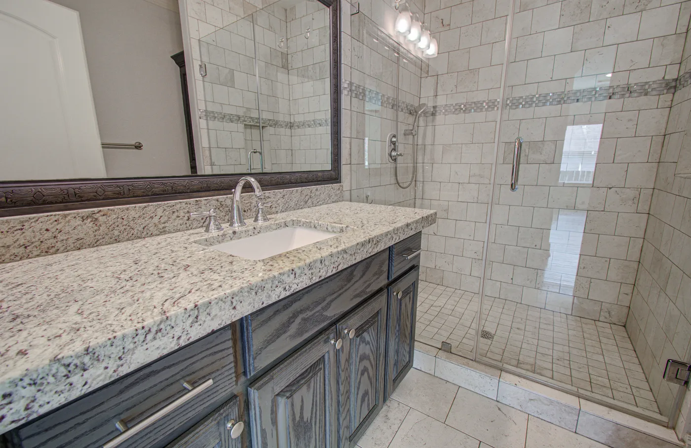 Tiled walk-in shower and granite vanity in a Houston Heights rental property
